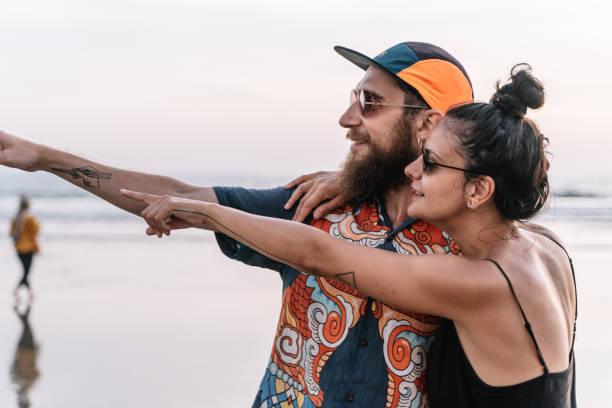 istock Modern couple with tattoos and piercings pointing at a beach 1198414691
