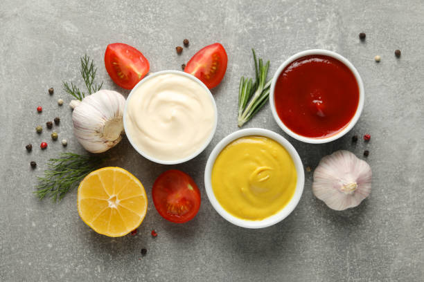 istock Set of different delicious sauces, garlic, cherry tomatoes on gray background, space for text. Top view 1198415071