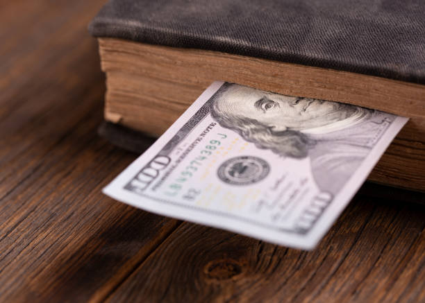 istock Dollar bill used as a bookmark in a book. One hundred US dollars 1198415169