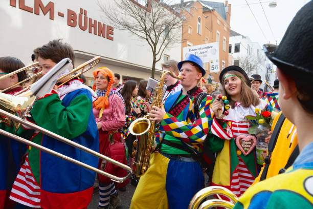 Bonn, Germany - February 28, 2019: Group of Adults, wearing the colorful costumes on Weiberfastnacht, Old Wives Day, marching in a parade, playing music with braa instruments