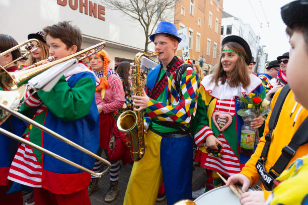 Bonn, Germany - February 28, 2019: Group of Adults, wearing the colorful costumes on Weiberfastnacht, Old Wives Day, marching in a parade, playing music with braa instruments