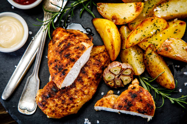istock Sliced grilled chicken breast and vegetables on black stone 1198417229