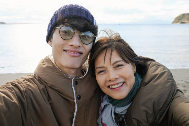 istock Active mature woman and her son taking selfie on beach 1198417442