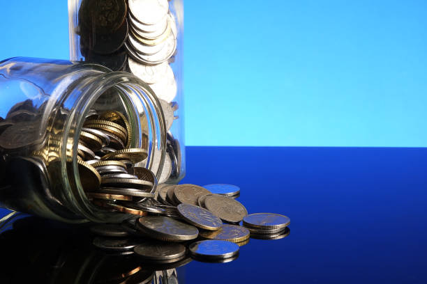 istock Saving concept with coins in a mason jar on a blue background. Copy space 1198418419