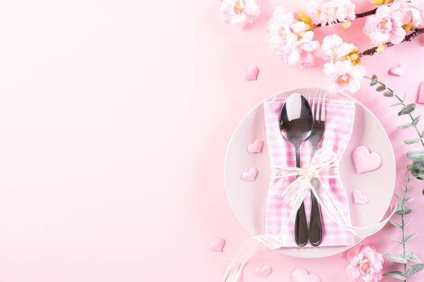 istock Pink paper hearts with table set with set of silverware fork and spoon on Light pink pastel paper background. Love and Valentine's day concept. 1198419396
