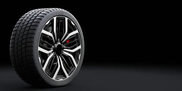 Wheel with modern alu rim on black background - banner composition. 3D illustration