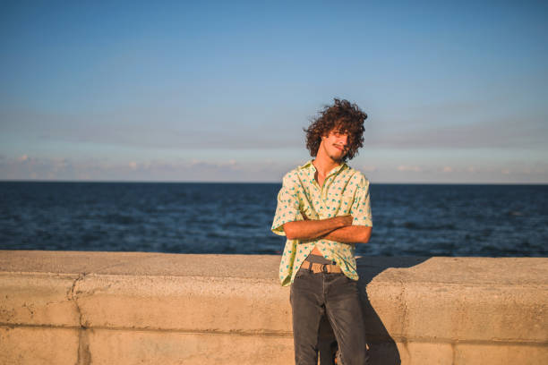 Young Latin American man looking at camera next to sea