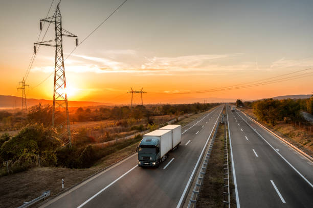 istock Blue transporter Truck with white trailer on highway at sunset 1198420522