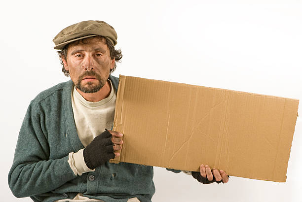 Beggar Holding a Cardboard and Wearing Worn Clothing stock photo