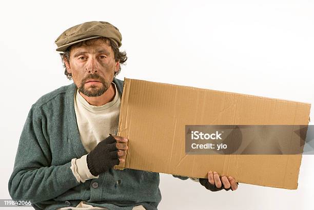 Beggar Holding A Cardboard And Wearing Worn Clothing Stock Photo - Download Image Now