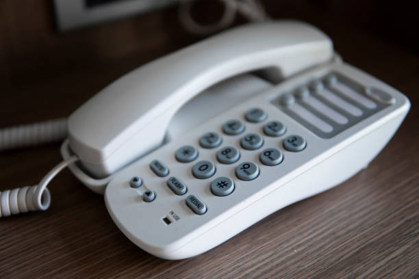 istock White vintage telephone with grey battoms on a brown table in hotel. 1198420791