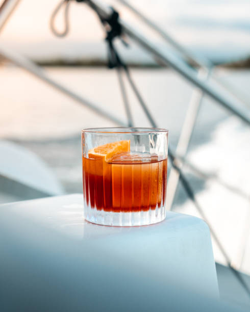 Negroni cocktail with big ice cube on a boat at sunset