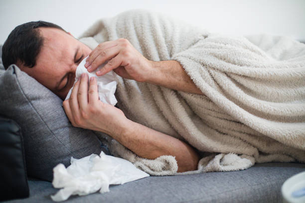 istock Man blowing his nose while lying sick in bed 1198421919