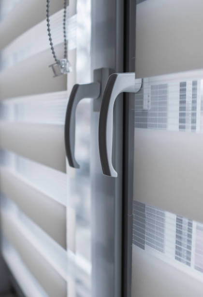 istock Window handle and white fabric roller blinds on the white plastic window in the living room. Close up on roll curtains indoor. 1198423248