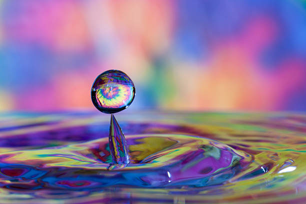 Water drop and splash with tie dyed background causing reflection stock photo