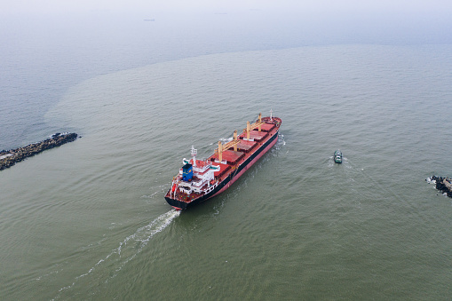 The pilot ship accompanies the cargo vessel at the exit from the shipping channel. Aerial drone shot taken in Kaliningrad region, Russia.