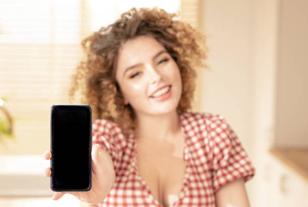 chica sonriente mostrando un teléfono móvil. - 16725 fotografías e imágenes de stock