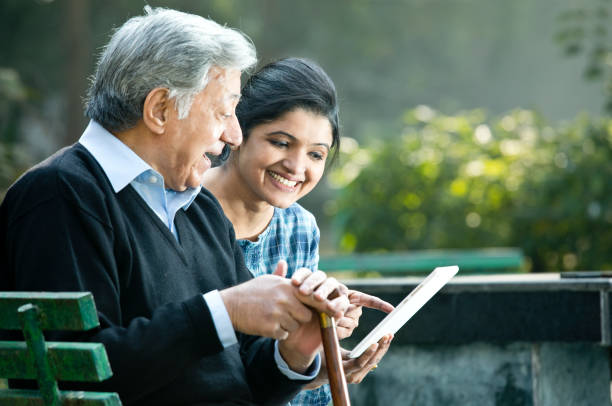 kobieta ze starym ojcem za pomocą cyfrowego tabletu w parku - father digital tablet asian ethnicity daughter zdjęcia i obrazy z banku zdjęć