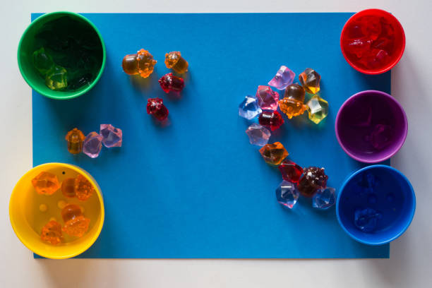istock Multicolored toy stones scattered on the blue surface and colorful cups for separating by color 1198426852