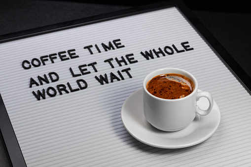 High angle view on white cup of coffee and letter board with inscription coffee time and let the whole world wait