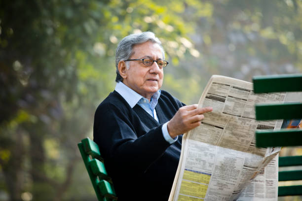 istock Senior man reading newspaper in the park 1198428992