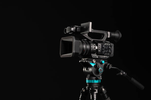 istock Professional 4K video camera on camera tripod on black background, copy space 1198429752