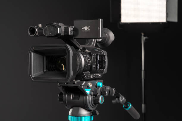 istock Professional 4K video camera on camera tripod and lighting LED panel on black background,close-up 1198429899