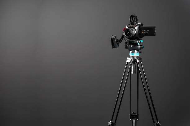 istock Professional video cinema camera on a camera tripod on black background copy space 1198429933