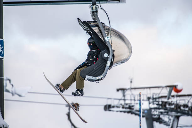 istock Man with Snowboard sitting on a Ski lift 1198434380