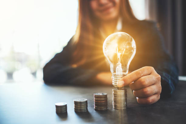 istock Businesswoman holding and putting lightbulb on coins stack 1198436242