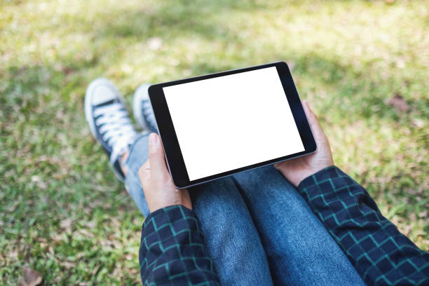 istock a woman holding and using black tablet pc with blank white desktop screen while sitting in the outdoors 1198436260