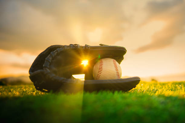 Baseball in glove in the lawn at sunset Baseball in glove in the lawn at sunset in the evening day with sun ray and lens flare light base sports equipment photos stock pictures, royalty-free photos & images