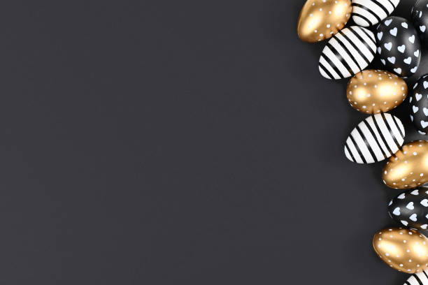 istock Flat lay with golden, black and white easter eggs painted with stripes, hearts and dots on black background with blank copy space 1198442093