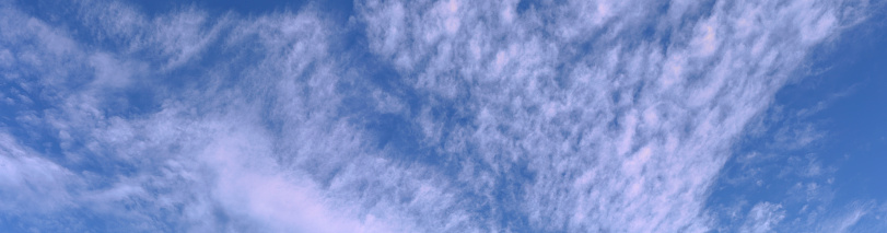 Wide panorama of high, white, fluffy clouds against a blue sky in UK winter.