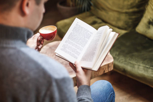 istock Man reading book and drinking coffee in the living room 1198445937