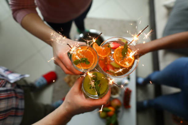 istock Young group friends hold in hand cocktail with sparkler 1198446036