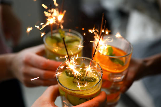 istock Young group friends hold in hand cocktail with sparkler 1198446038