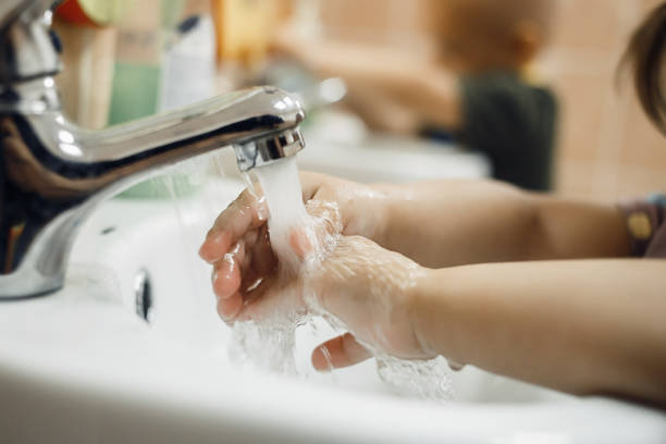 Toddlers wash their hands in a washstand in kindergarten. Concept of hygiene, professional childcare stock photo
