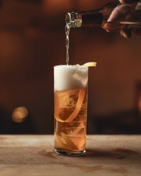 Horses Neck Cocktail with a hand pouring the ginger ale