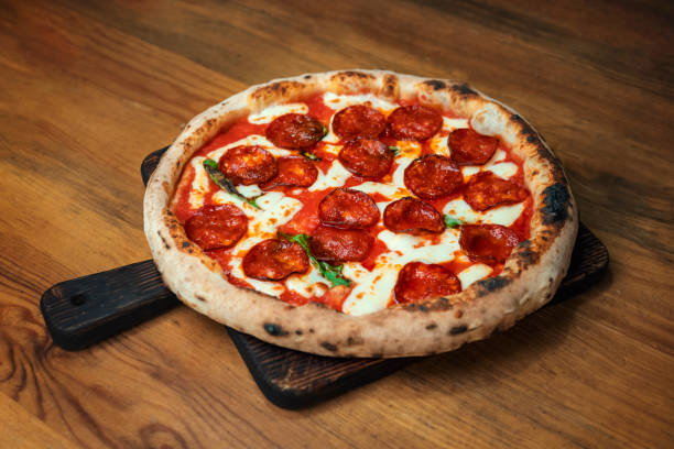 istock Freshly baked pizza with ingredients on a wooden table 1198447411