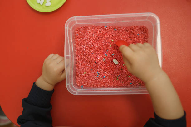 Children play educational games with a sensory bin in kindergarten.
