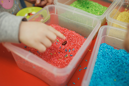 Children play educational games with a sensory bin in kindergarten.
