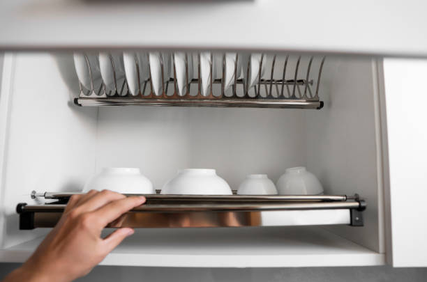 istock Dish drying metal rack with big nice white clean plates. Traditional comfortable kitchen. Open white dish draining closet with wet dishes of glass and ceramic, plates, bowls drying inside on rack. 1198452287