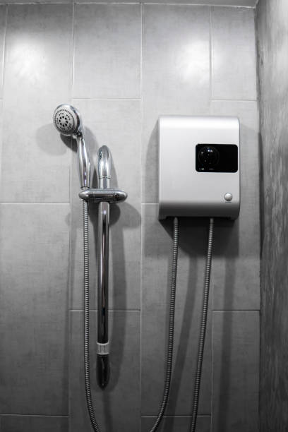 istock Instant tankless electric water heater installed on grey tile wall with input and output pipe outlet and elcb safety breaker system and silver shower. 1198453734