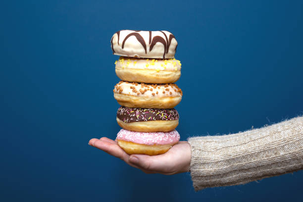 istock Stack of assorted delicious colorful donuts near dark blue background, sugar concept 1198454185