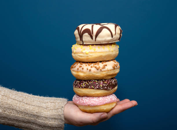 istock Stack of assorted delicious colorful donuts near dark blue background, sugar concept 1198454305