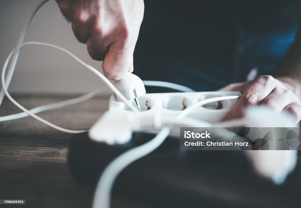 hand plugging power cord into power strip outlet close-up of hand plugging power cable into power strip outlet Cable Stock Photo
