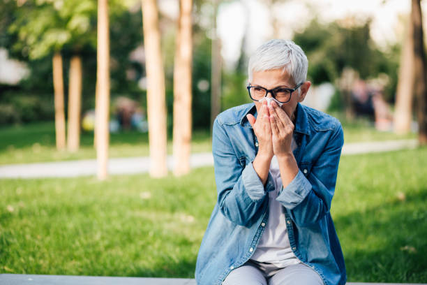 Senior woman has allergy Woman sitting in the park and sneezing allergy test stock pictures, royalty-free photos & images