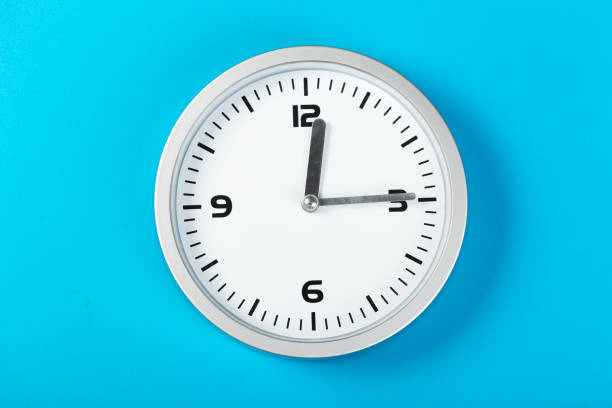 istock minimalistic white wall clock with light metal on a blue background. time concept. 1198462628