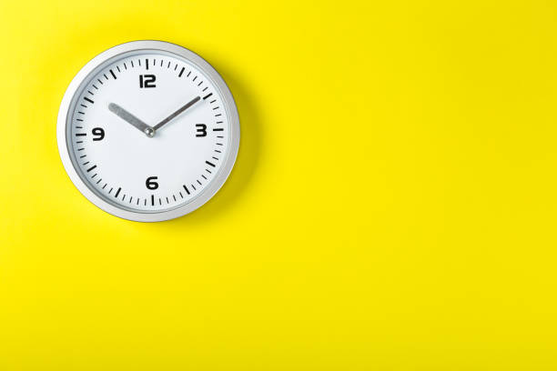 istock minimalist white wall clock with light metal on a yellow background. time concept. 1198462640